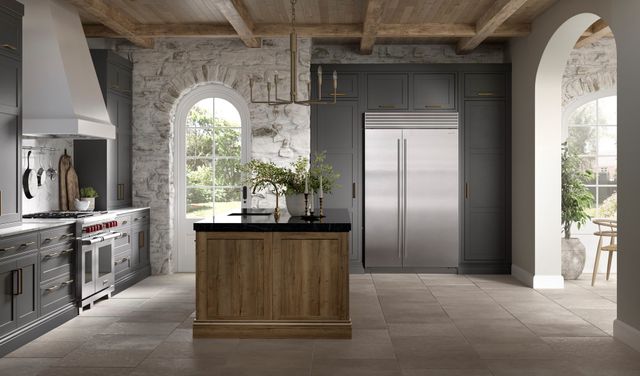 front view of a modern rustic kitchen with white brick walls, grey cabients, and a stainless steel refrigerator